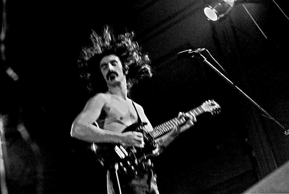 Frank Zappa tocando la guitarra en vivo, ícono de la música experimental y el rock progresivo