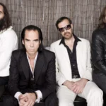 Nick Cave & The Bad Seeds en una sesión fotográfica, mostrando su estilo oscuro y elegante característico del rock alternativo